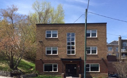 a red brick house with windows on a street